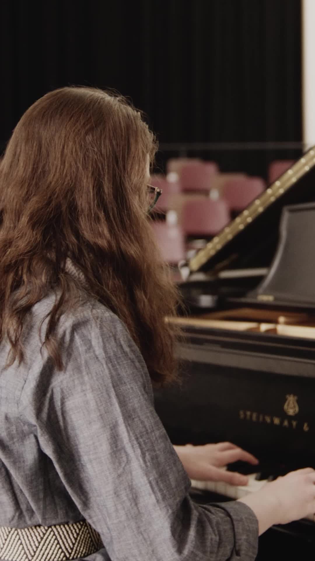 Pangaea Finn, a concert pianist and biophysics researcher playing the piano in a music room.
